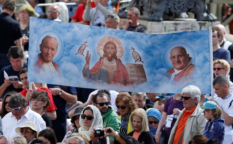 A banner shows new Sts John Paul II and John XXIII and Jesus during an April 28 Mass of thanksgiving for the canonisations of the new saints in St Peter's Square at the Vatican. Photo: CNS/Paul Haring
