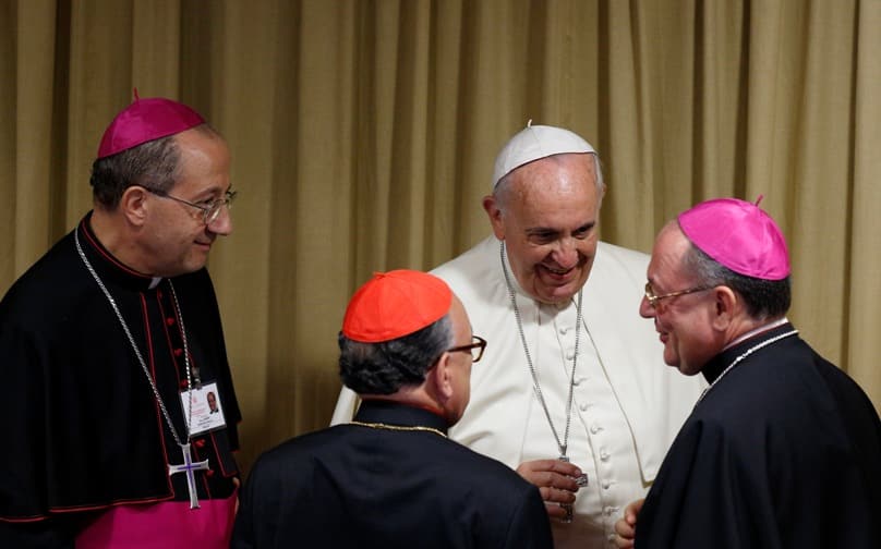 Pope Francis talks with Cardinal Raymundo Damasceno Assis of Aparecida, Brazil, and Bishop Fabio Fabene, under-secretary of Synod of Bishops, before the morning session of the extraordinary Synod of Bishops on the family at the Vatican on 18 October, 2014. Photo: CNS/Paul Haring