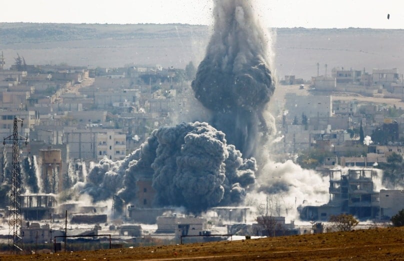 An explosion following an October 2014 air strike is seen in the Syrian town of Kobani from the Turkish-border town of Suruc. Photo: CNS/Yannis Behrakis, Reuters