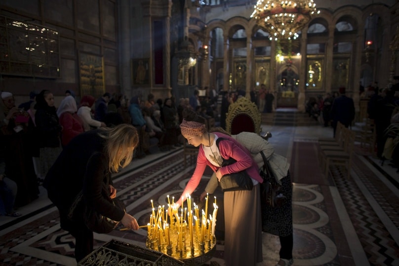 Women light candles in the Church of the Holy Sepulchre in Jerusalem’s Old City on Easter Sunday this year. Photo: Ronen Zvulun, Reuters