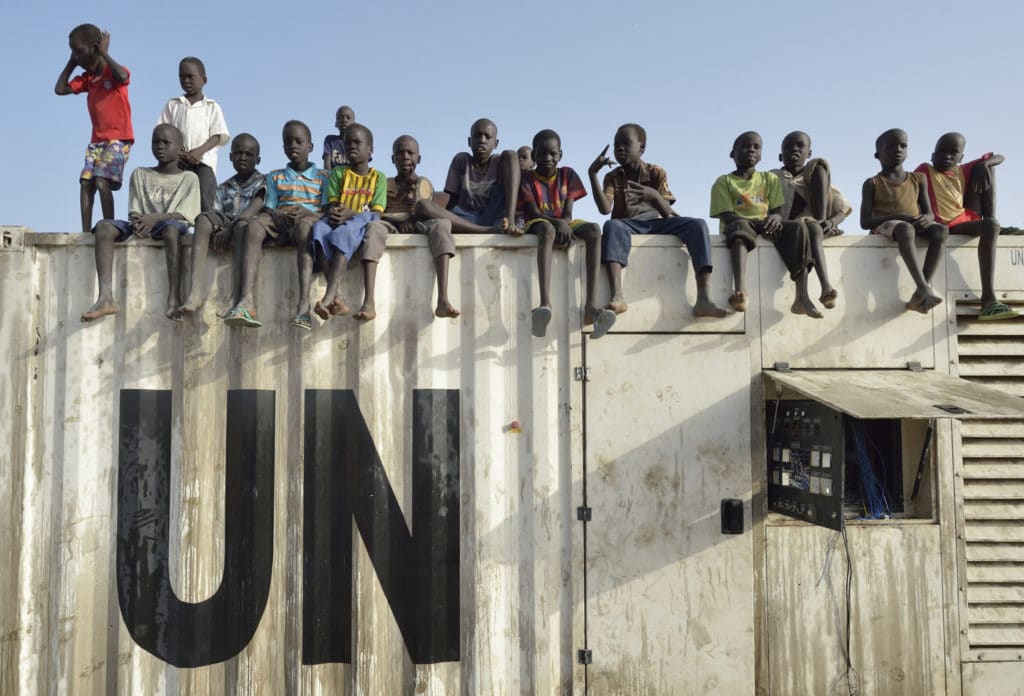 Children sit atop a structure inside a U.N. base in Malakal, South Sudan. More than 20,000 civilians have lived inside the base since shortly after regional fighting broke out in December 2013, but renewed fighting in 2015 drove another 5000 people into the relative safety of the camp. Photo: CNS/Paul Jeffrey