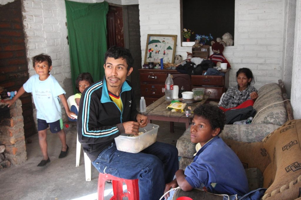 Ricardo Lemos, 28, shreds cooked chicken for sandwiches his wife sells daily in Quito, Ecuador. The family fled violence in Colombia. Photo: CNS/Barbara Fraser