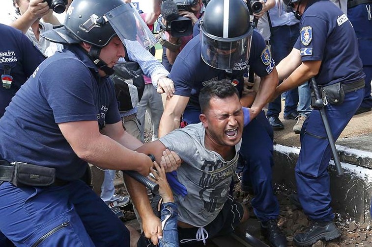 Hungarian policemen detain migrants on the tracks at a railway station in the town of Bicske, Hungary, on 3 September. Photo: CNS/Laszlo Balogh, Reuters