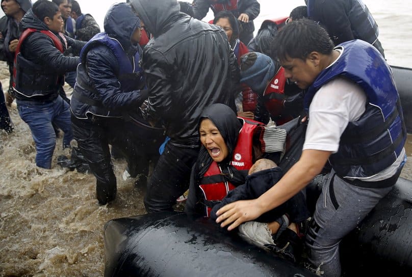 Afghan mother holds her baby as she struggles to disembark raft during a rainstorm in Lesbos, Greece, on 23 October. Photo: CNS/Yannis Behrakis, Reuters 