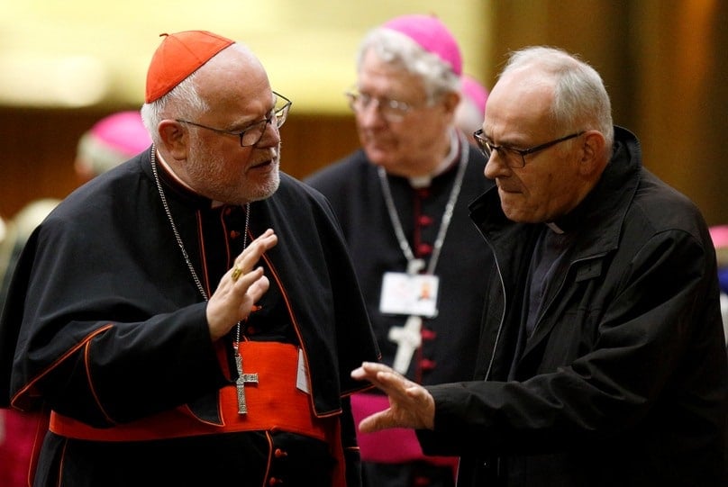 Cardinal Reinhard Marx of Munich-Freising, president of the German bishops' conference, talks with an unidentified delegate as they leave the final session of the Synod of Bishops on the family at the Vatican on 24 October. Photo: CNS/Paul Haring