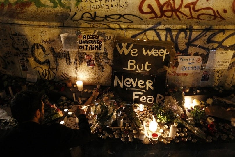 A man lights a candle in Republique square in Paris on 14 November in memory of victims of terrorist attacks. Photo: CNS photo/Paul Haring.