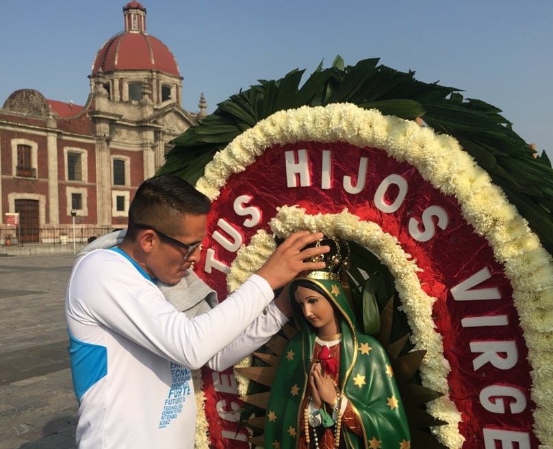 A man adjusts the crown on a statue of Our Lady of Guadalupe outside the basilica named for her in northern Mexico City. Photo: CNS/David Agren 