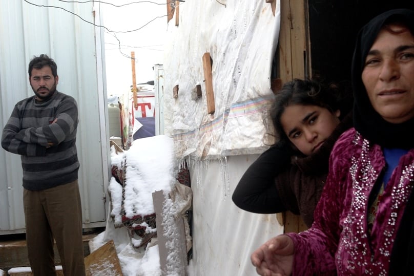 Syrian refugees stand in snow outside their tents on 2 January in Lebanon's Bekaa Valley.Photo: CNS /Lucie Parsaghian, EPA