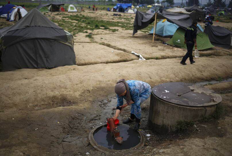 A woman collects water at a makeshift camp for migrants and refugees at the Greek-Macedonian border near the village of Idomeni, Greece. Photo: Stoyan Nenov, Reuters