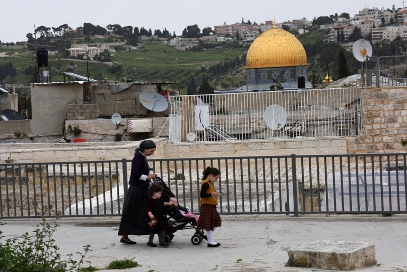 An Orthodox Jewish woman walks with her children on the roof in the Arab section of the Old City of Jerusalem on her way from an Israeli settlement on 26 March. The Jewish settlement is near the Church of the Holy Sepulchre and the Church of the Redeemer in the Christian Quarter of the Old City. Photo: CNS/Debbie Hill