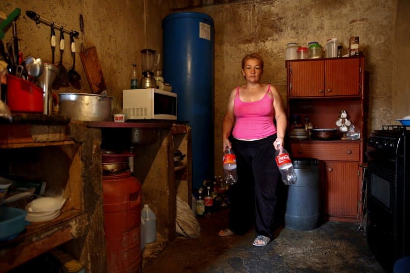 Yunni Perez holds plastic bottles used to carry water while she poses for a photo on 3 April inside her home in a slum area of Caracas, Venezuela. Photo: CNS/Carlos Garcia Rawlins, EPA