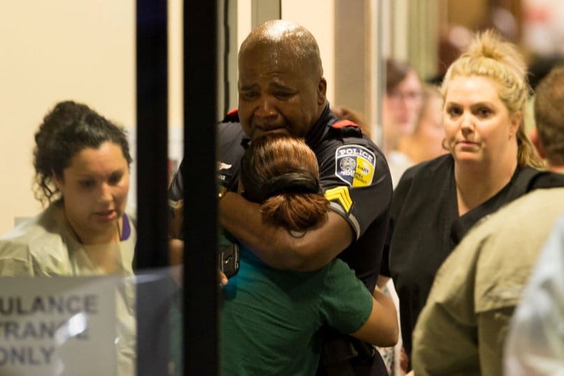 A Dallas police officer is comforted at Baylor University Hospital's emergency room entrance after a shooting attack. Photo: CNS/Ting Shen, The Dallas Morning News via Reuters