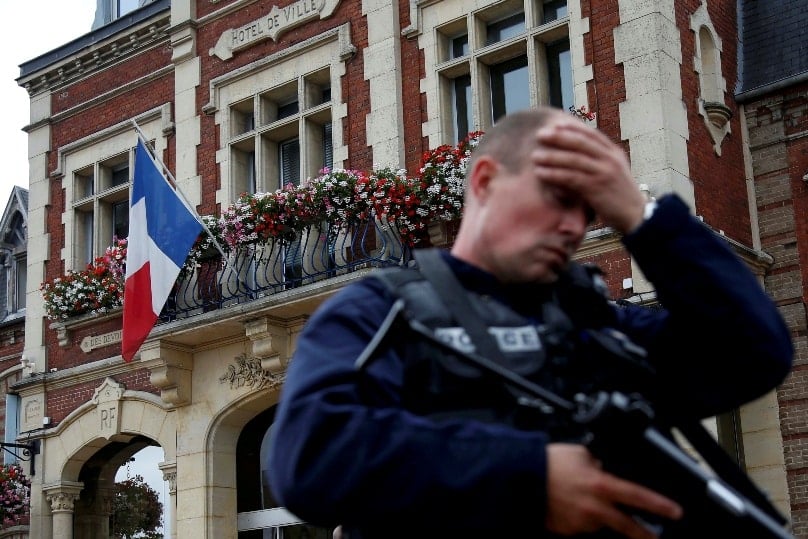 A policeman reacts as he secures a position in front of city hall after two assailants killed 84-year-old Fr Jacques Hamel and took five people hostage during a weekday morning Mass at the church in Saint-Etienne-du-Rouvray, France, near Rouen on 26 July. Photo: CNS/Pascal Rossignol/Reuters