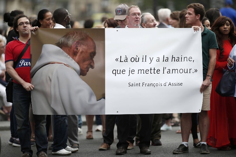 People hold a banner with a picture of French priest Father Jacques Hamel, which reads, "Where there is hatred, let me sow love," after a July 27 Mass at the Notre Dame Cathedral in Paris. Father Jacques Hamel was killed in a July 26 attack on a church at Saint-Etienne-du-Rouvray near Rouen by assailants linked to Islamic State groups. Photo: CNS