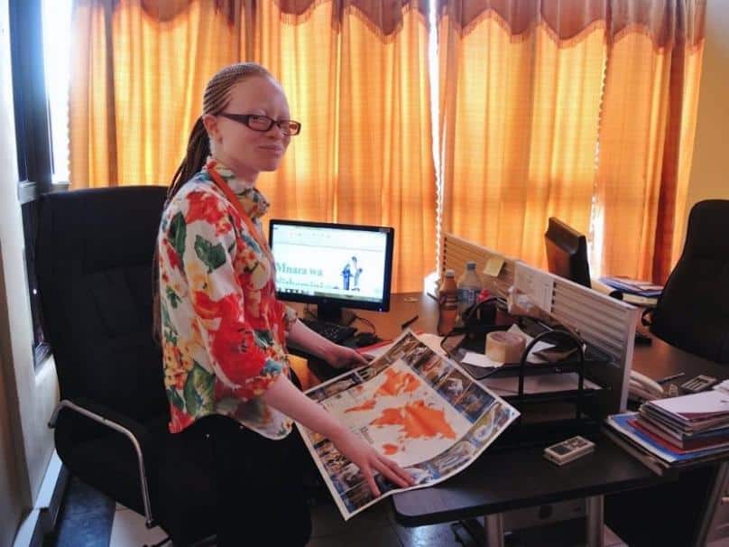 Perpetua "Perry" Senkoro, a lawyer who has albinism, works at Under the Same Sun, an activism organisation. She shows one of the posters with pictures of people from around the world who have albinism, one of the "aha!" moments during the village seminars where the organisation tries to help people understand that albinism is a genetic condition and their body parts do not have supernatural powers. Photo: GSR/Melanie Lidman