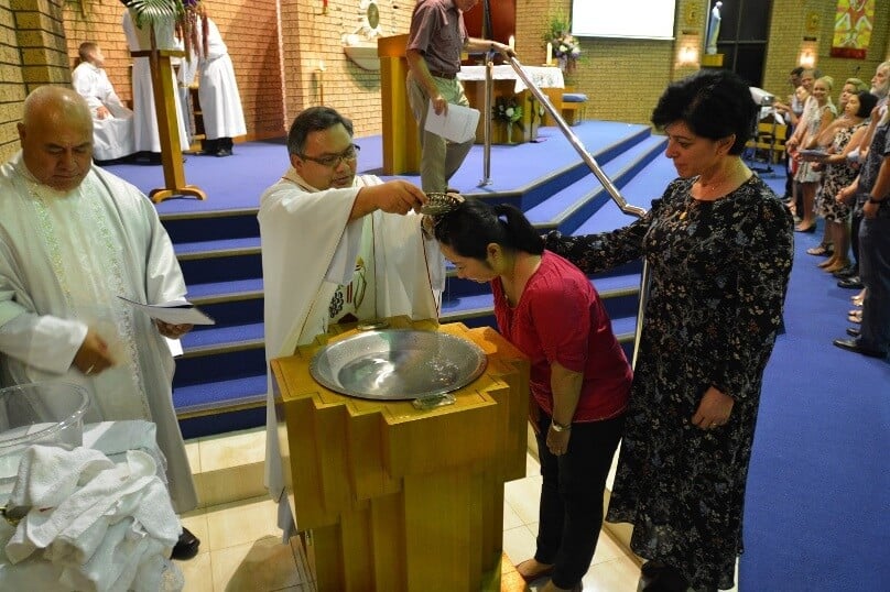 Winston Hill assistant priest Fr Tovia Lui, parish priest Fr Ranillo Creta baptise Sharon Wang, pictured with sponsor Nancy Hargrave.