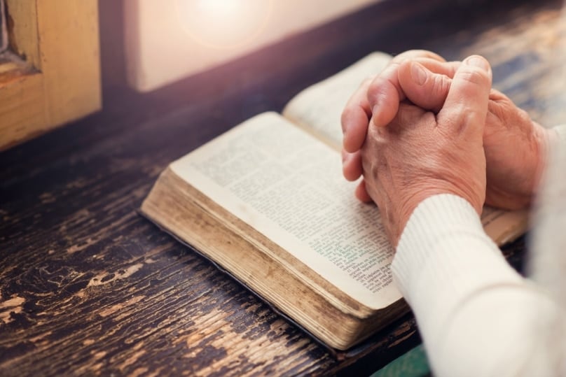 shutterstock_334942148-older-woman-praying-hands-bible