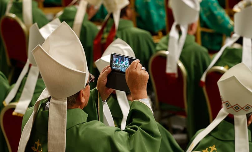 A bishop takes a photo as Pope Francis celebrates the closing Mass of the Synod of Bishops on young people, the faith and vocational discernment in St. Peter's Basilica at the Vatican. Photo: CNS photo/Paul Haring