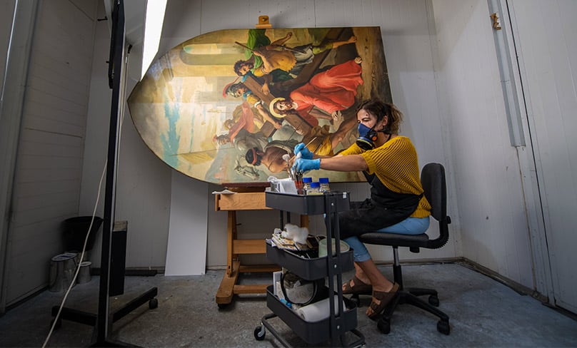 One of the restorers in her studio with one of the Stations of the Cross. Photo: Giovanni Portelli