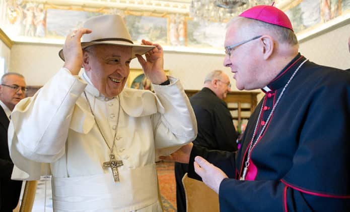 Pope Francis tries on a hat presented by Archbishop Mark Coleridge of Brisbane. Photo: CNS photo/Vatican Media