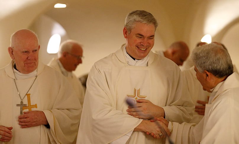 Bishop Gerard Holohan of Bunbury, Australia, left, and Auxiliary Bishop Richard Umbers of Sydney and other Australian bishops exchange the sign of peace as they concelebrate Mass in the crypt of St. Peter's Basilica at the Vatican June 24, 2019. Photo: CNS photo/Paul Haring