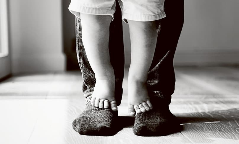 Child stands on father's feet.