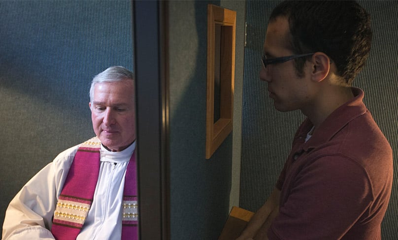 Father Timothy J. Mockaitis, pastor of Queen of Peace Catholic Church in Salem, Ore., and penitent Ethan K. Alano of Salem demonstrate how a confession is conducted May 3, 2019. Photo: CNS photo/Chaz Muth