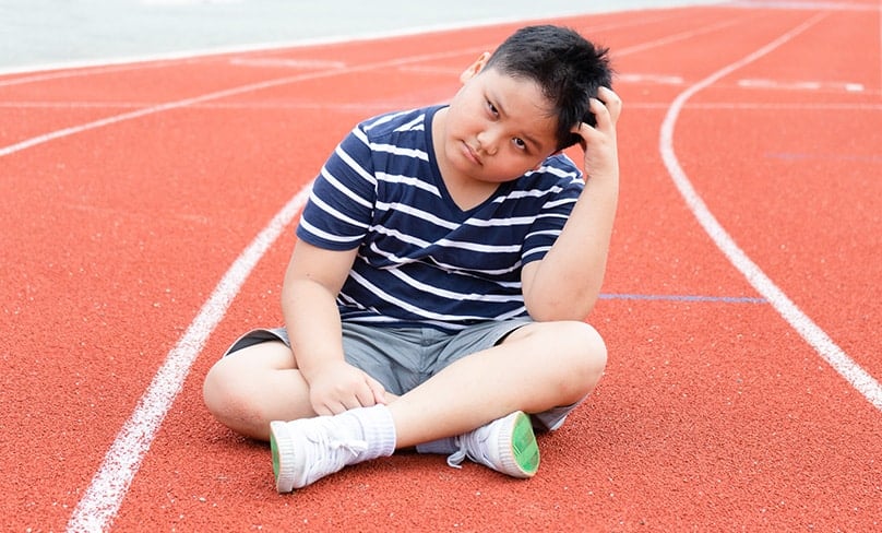 Bored child sits on running track.