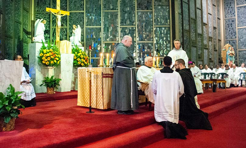 Brother Bernard Mary Fonkalsrud OFM Conv solemnly professes his vows while placing his hands on the Holy Gospel. Photo: Mathew De Sousa 