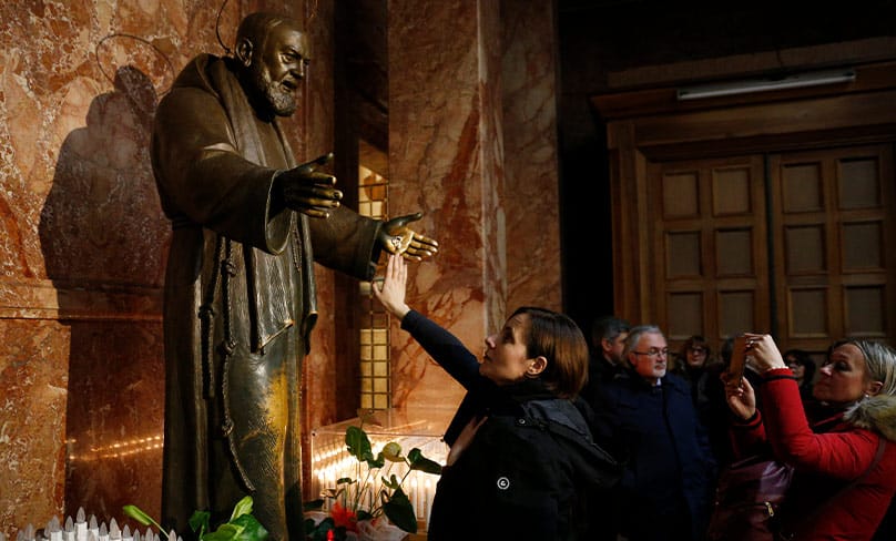A woman touches a statue of St. Padre Pio in the Church of Santa Maria delle Grazie at the Shrine of St. Pio of Pietrelcina in San Giovanni Rotondo. Photo: CNS photo/Paul Haring