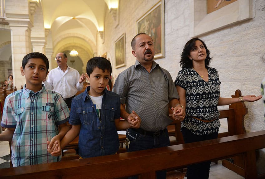 A family prays during Mass in the Church of St Catherine in Bethlehem,Israel. Photo: CNS, Debbie Hill