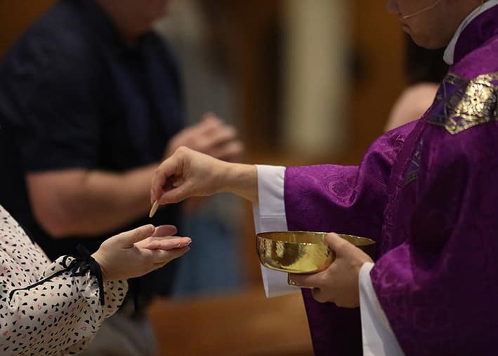 Father Andy Hammeke distributes Holy Communion during a March 15, 2020, Mass at St. Mary Queen of the Universe Church in Salina, Kansas. Photo: CNS photo/Karen Bonar, The Register
