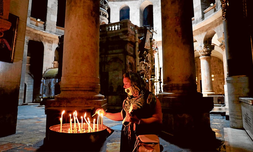 Visit virtually: a worshipper wears a a protective mask in the Church of the Holy Sepulchre in Jerusalem. Photo: CNS/Debbie Hill