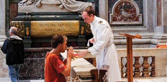 Then-deacon Patrick Lewis, now a priest of the Archdiocese of Washington, distributes Communion during a private Mass at a chapel in St Peter’s Basilica at the Vatican in 2011. Photo: CNS photo/Paul Haring