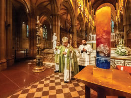 A candle symbolising the Plenary Council stands in St Mary’s Cathedral as Archbishop Anthony Fisher and clergy process out of the cathedral following the commissioning ceremony. Photo: Giovanni Portelli