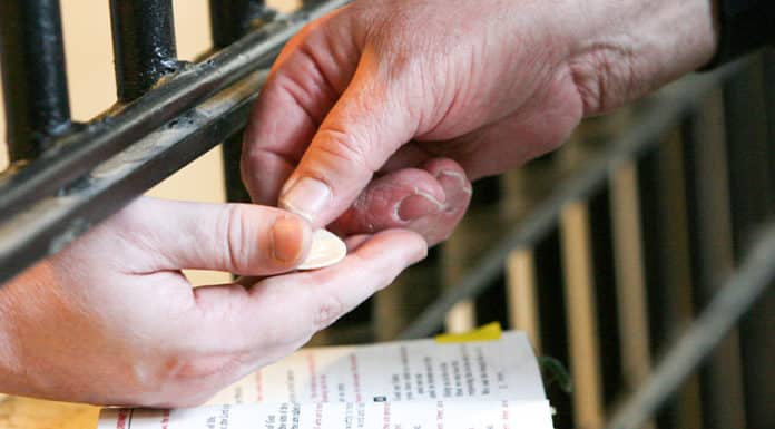 When I was in jail, you visited me: a US prison chaplain, main photo, delivers Communion to a prisoner. Photo: Karen Callaway, Northwest Indiana Catholic