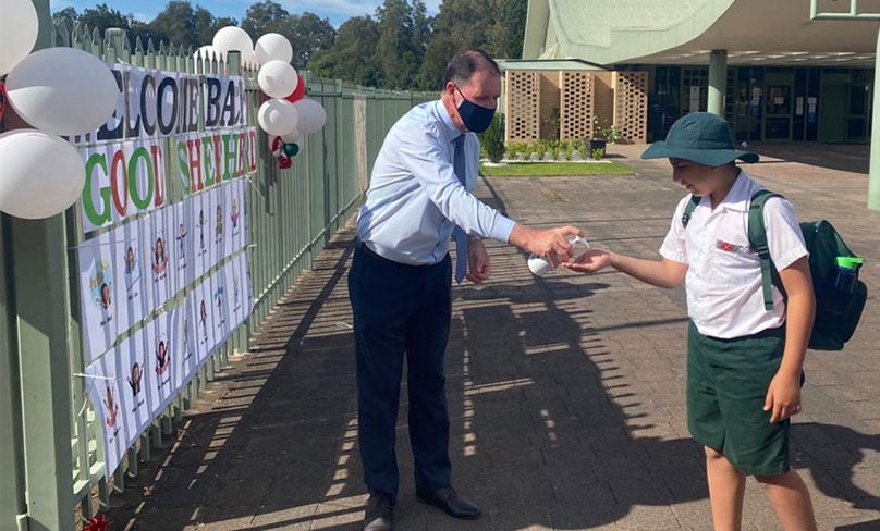 Good Shepherd Primary Principal Brendan O'Connor sanitising students hands as they enter the school gates post lockdown. Photo: Supplied