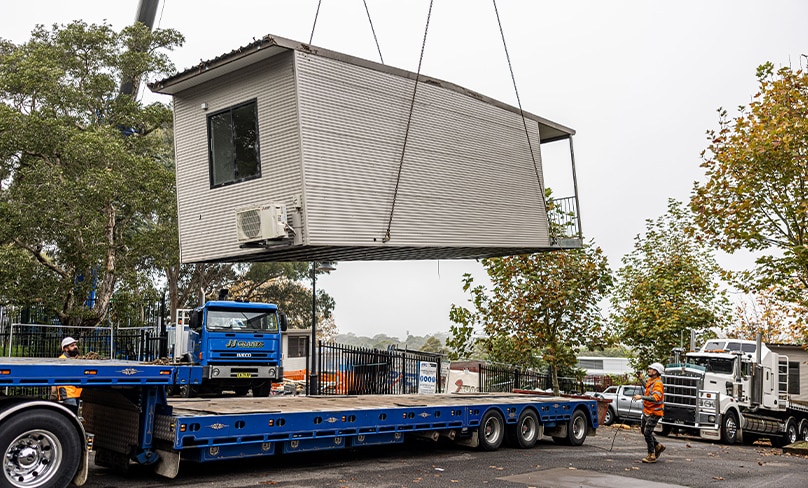 A state-of-the-art demountable classroom, provided by Sydney Catholic Schools, is lowered on a truck before being transported to Trinity Catholic College, LIsmore. Photo: Alphonsus Fok