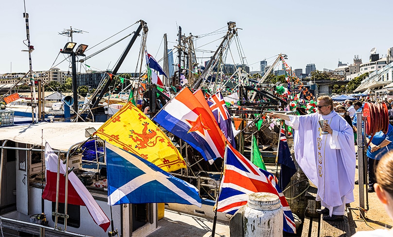 Amid a riot of colour and flags, Scalabrinian priest Fr Jose Gutierrez cs, at left, blesses the fishing fleet at Sydney’s Fish Markets last weekend. Photo: Alphonsus Fok