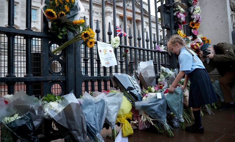 A girl places flowers outside Buckingham Palace in London Sept. 8, 2022, after Queen Elizabeth II -- Britain's longest-reigning monarch and the nation's figurehead for seven decades -- died at the age of 96. Photo: CNS photo/Henry Nicholls, Reuters