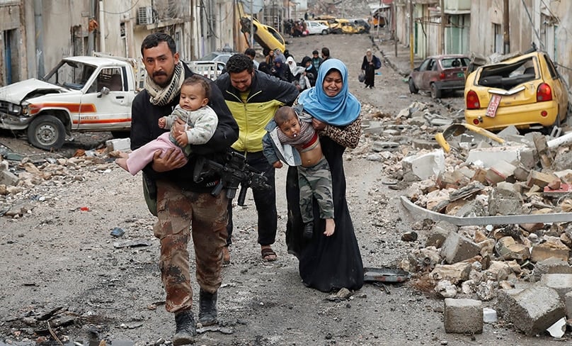 An Iraqi soldier helps a family carry their child to cross from an Islamic State-controlled part of Mosul to an area controlled by Iraqi forces during the battle for Mosul in 2017. Photos: CNS photo/Goran Tomasevic, Reuters