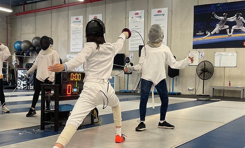 Megan Lam, left, lunges at her opponent in the NSW Fencing Centre. Photo: Supplied