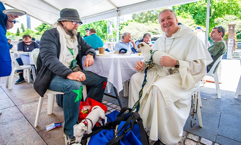 Archbishop Anthony Fisher OP holds man’s best friend as he chats with a guest at this year’s Street Feast. Photo: Giovanni Portelli