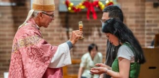 Bishop Daniel Meagher blesses a couple with a relic of St Gerard Majella, the patron saint of mothers, at St Paul of the Cross in Dulwich Hill. Photo: Giovanni Portelli