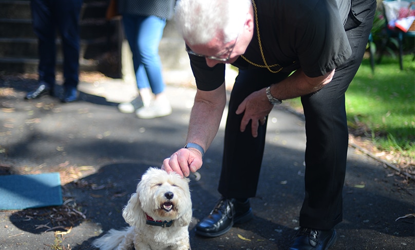Monsignor Carl Reid greets one of the paw-rishioners of St Joseph’s, Newtown. Photo: Supplied