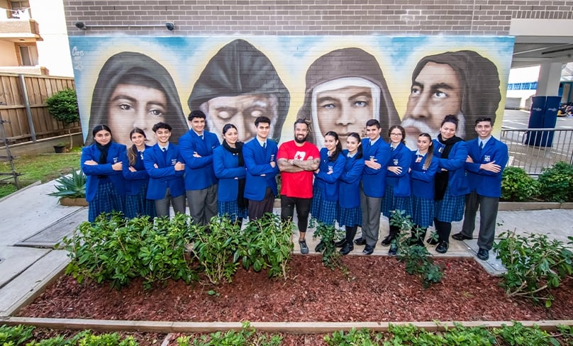 Graffitti artist Danny Mulyono stand in front of the mural with students at the Maronite College of the Holy Family at Harris Park Photo: Giovanni Portelli