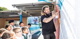 Danny Mulyono shows St Peter Chanel Primary School students the art of spray-painting a mural. Photo: Giovanni Portelli