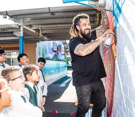 Danny Mulyono shows St Peter Chanel Primary School students the art of spray-painting a mural. Photo: Giovanni Portelli