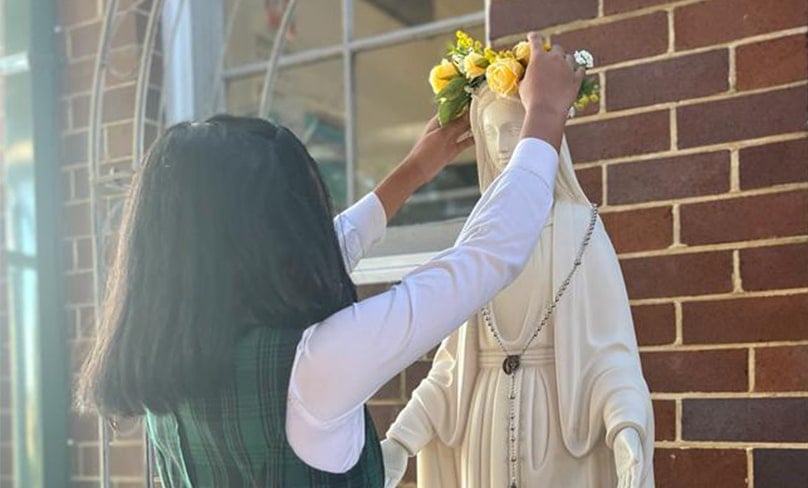 A student crowns a statue of Our Lady at St Peter Chanel Catholic Primary School, Regents Park. Photo: Supplied