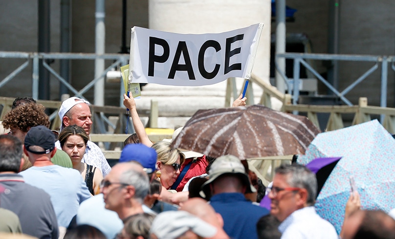 A person holds up a banner that reads "Pace" -- "peace" -- as visitors gather in St. Peter's Square at the Vatican to pray the Angelus with Pope Francis June 18, 2023. Photo: CNS photo/Lola Gomez